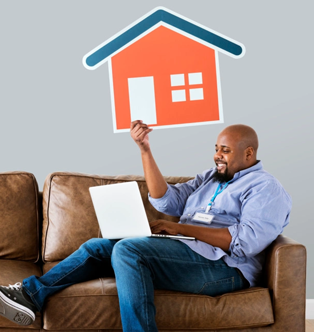 Mortgage-right Man on couch, holding house icon, laptop.