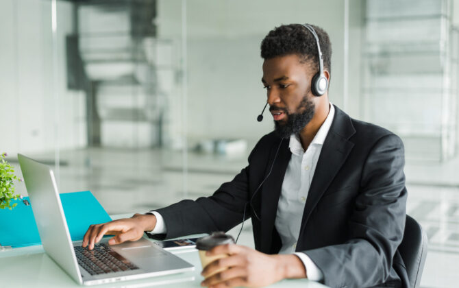 Businessman using laptop and headset.