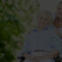 Smiling senior woman with caregiver outdoors.
